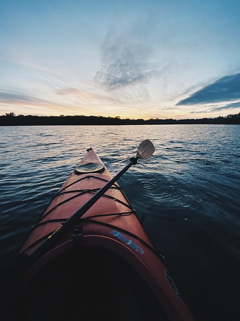 Kayaker paddling through a serene lake at sunrise, representing water adventures.
